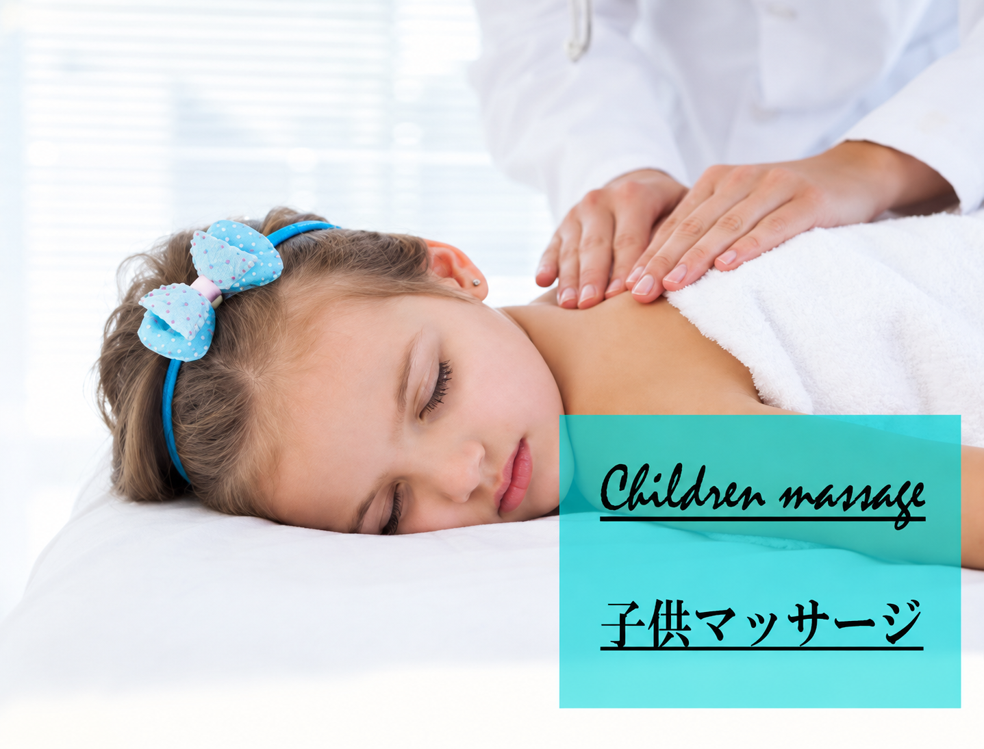 A child resting under a white towel while a therapist gently massages her upper back